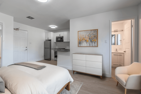 A bedroom with a bed, a chair, and a painting on the wall. at 608 Church Apartments, Toronto, ON